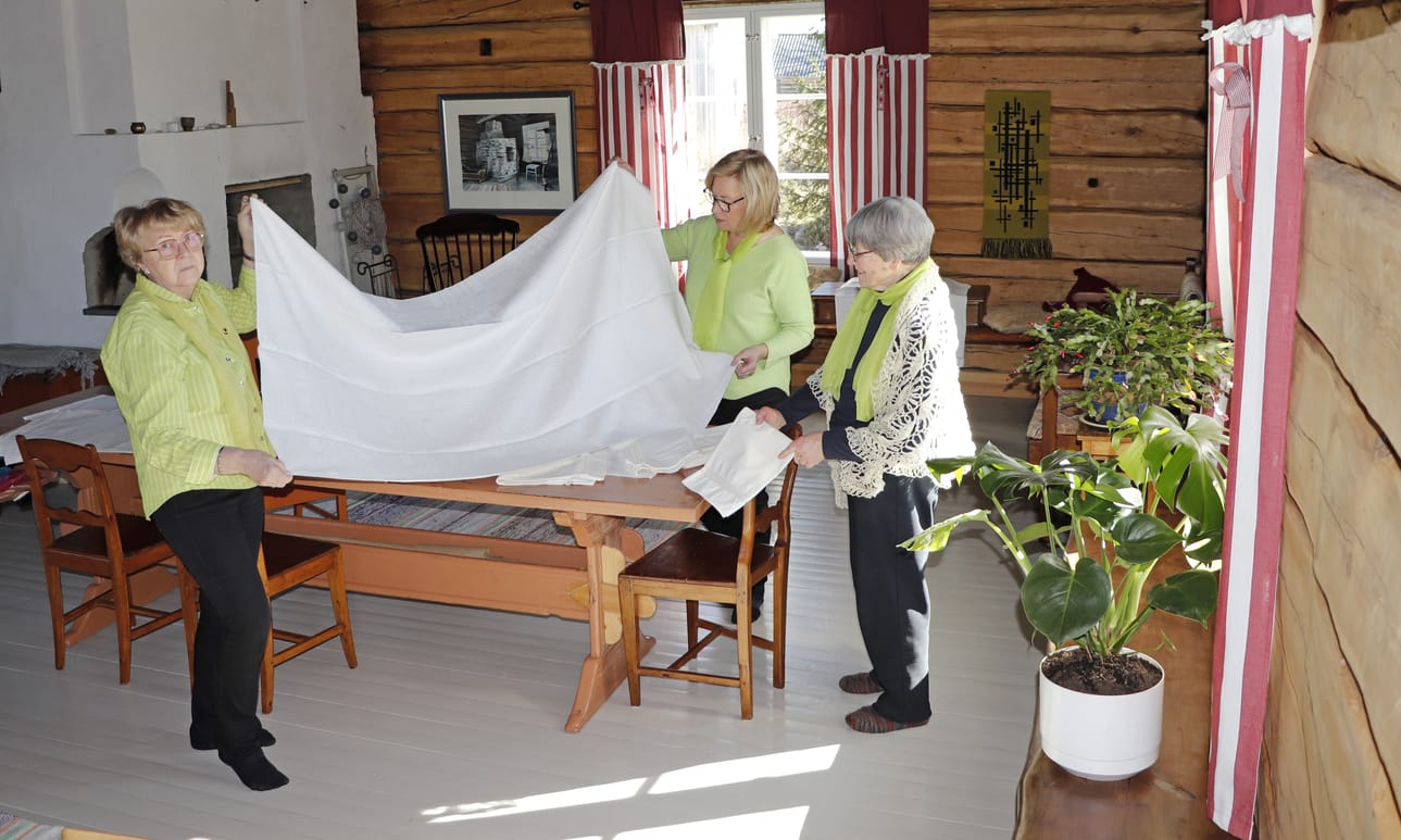 Elvi Räisänen, Maija Lax ja Saara Hintikka katsovat Anni Sankalan itse kasvatetuista pellavista Pudasjärvellä kutomaa liinaa.