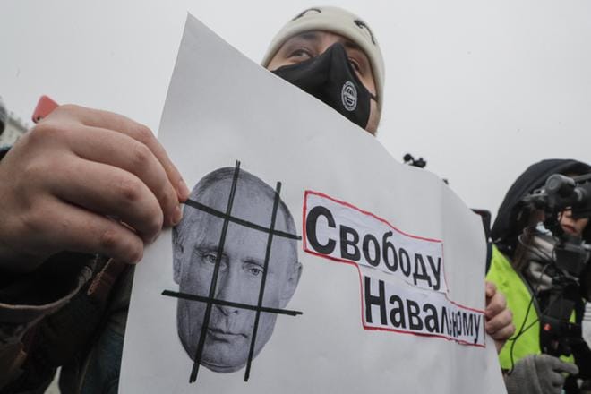 Protestoija pitelee lappua, jossa vaaditaan vapautta Navalnyille. Kaltereiden taakse toivotetaan puolestaan Putinia. KUVA: Maxim Shipenkov/EPA