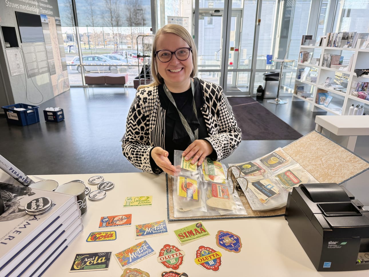 Amanuenssi Saija Pietiläinen valitsi näyttelyyn olut- ja virvokejuomapullojen etikettejä.
