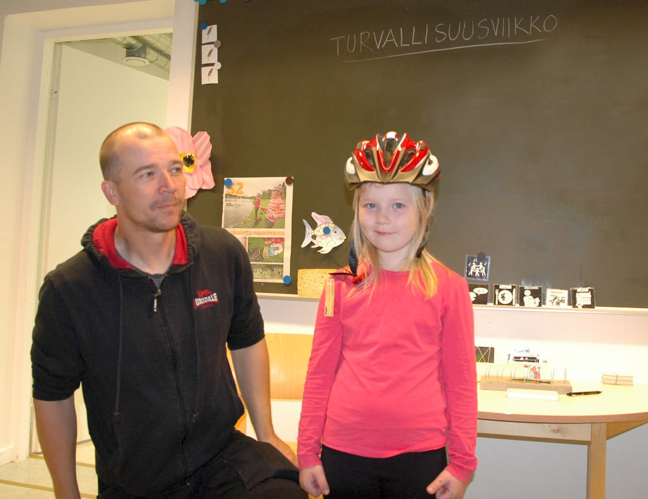 Pyhännän vapaa-ajanohjaaja Matti Saaranen sovittaa pyöräilykypärää Seela Aitto-ojan päähän.
