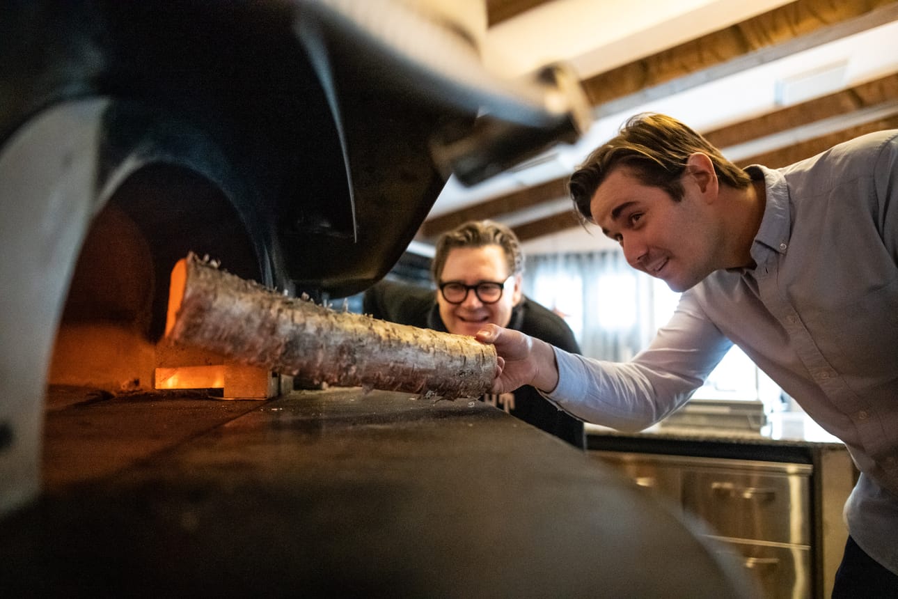 Pizzauuni lämpiää Rukalla heti aamupäivästä. Henrik lisää puita Paavon seuratessa taustalla. Myös yrityksessä asetelma on sama.