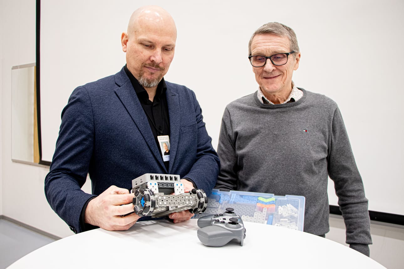 Siikajoen lukion rehtori Juha Vaara ja Ari Haapakoski tutkivat malliksi koottua robottia. Haapakoski pitelee robotin rakennussarjaa.