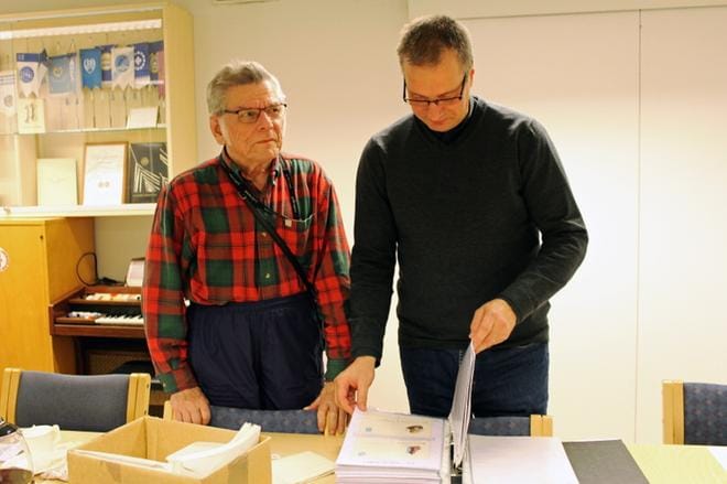 Taisto Setälä ja Tuomas Rouhunkoski tutkivat edesmenneen puheenjohtajan Esko Tuomolan yksityiskohtaista Suomi maailmalla -kokoelmaa. KUVAT: TARJA RIIHIMÄKI