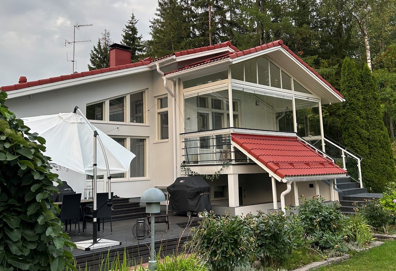 Iso puutarhatontti ympäröi näyttävää 90-luvun taloa. Erilaiset tasot, katokset ja ikkunoiden muodot ovat aikakaudelle tyypillisiä. Kuva: Anne Lind