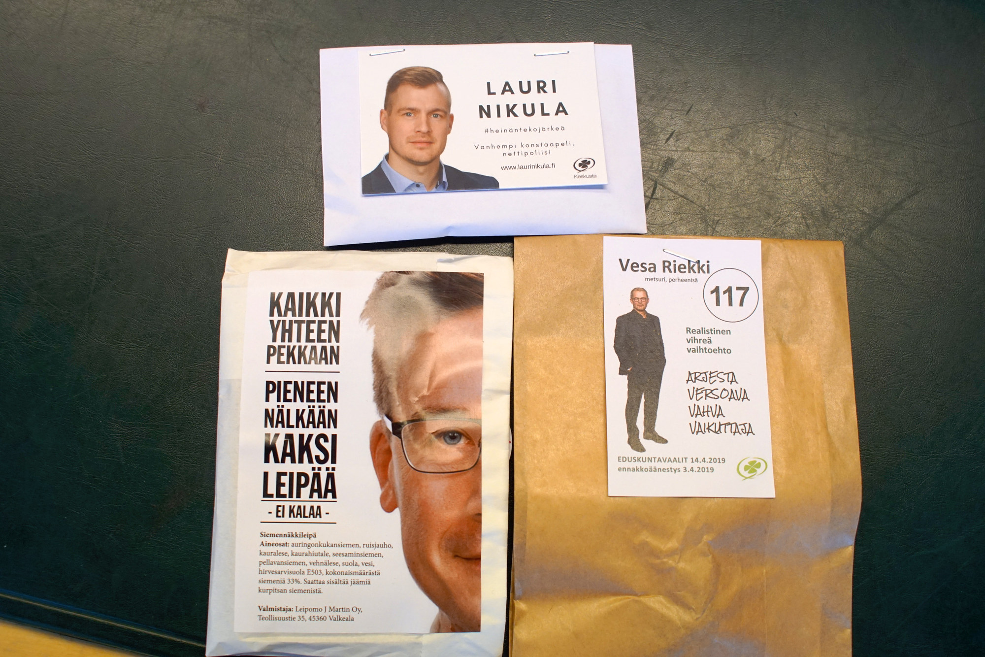 Lauri Nikulan vaalipussista löytyy rairuohon siemeniä, Vesa Riekin pussista käpy metsänviljelyohjeineen. Pekka Aittakumpu luottaa leipään.