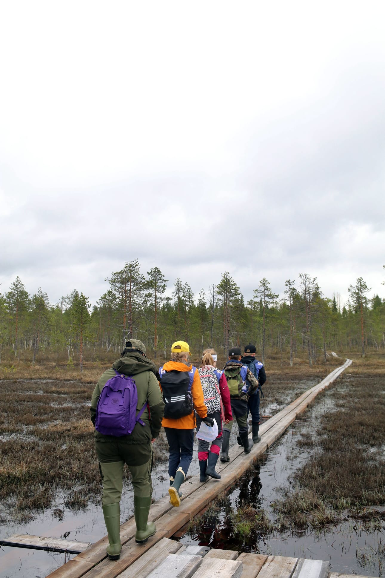 Kisa käynnissä. 5A-luokan joukkue suuntaa pitkoksia pitkin kohti rastia. Viimeisenä jonossa kävelee opettaja Auli Näsi.