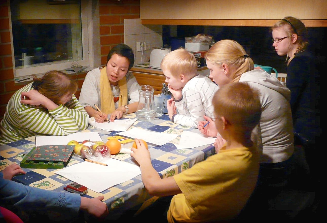 Kiinalaisten kirjoitusmerkkien opiskelua Säkkisillä. Kuvassa Raija Säkkinen, Ni Heya sekä lapset Mio, Anna, Aino ja Olli. Takana Jukka Säkkinen.