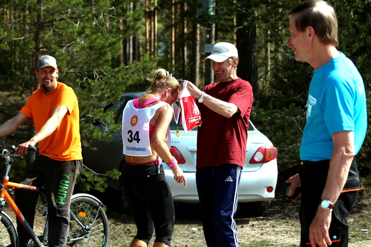 Kisaisäntä Paavo Leiviskä jakoi mitaleita ja onnitteli juoksijoita maalissa. Mitalia vastaanottamassa N50-sarjan kakkonen Kati Kuivalainen.