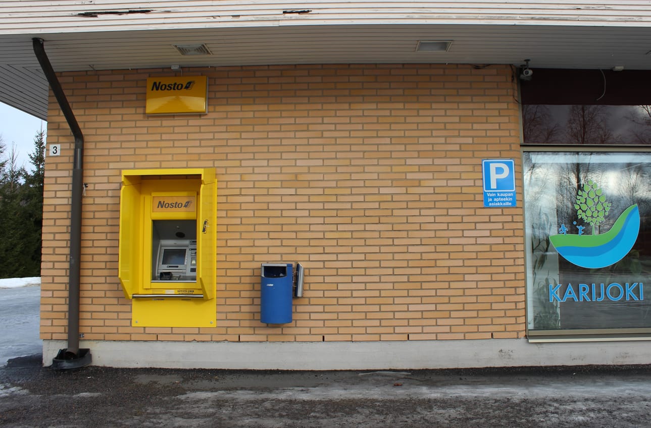 Pankkiautomaatti sijaitsee kirjastorakennuksen seinässä.