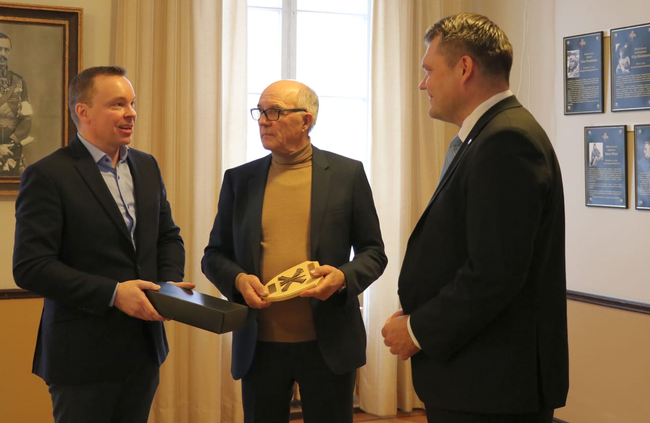 LSK Business Parkin toimitusjohtaja Jouko Pihlajamaa (kuvassa keskellä) vastaanotti puolustusministeriön plaketin puolustusministeri Mikko Savolalta. Toimitusjohtaja Mika Marjamäki (vas.) antoi ministerille kiitokseksi vierailusta kaksineuvoisen hevosenpääpuukon, koska tavan mukaan ilman puukkoahan ei voi Kauhavalta lähteä.