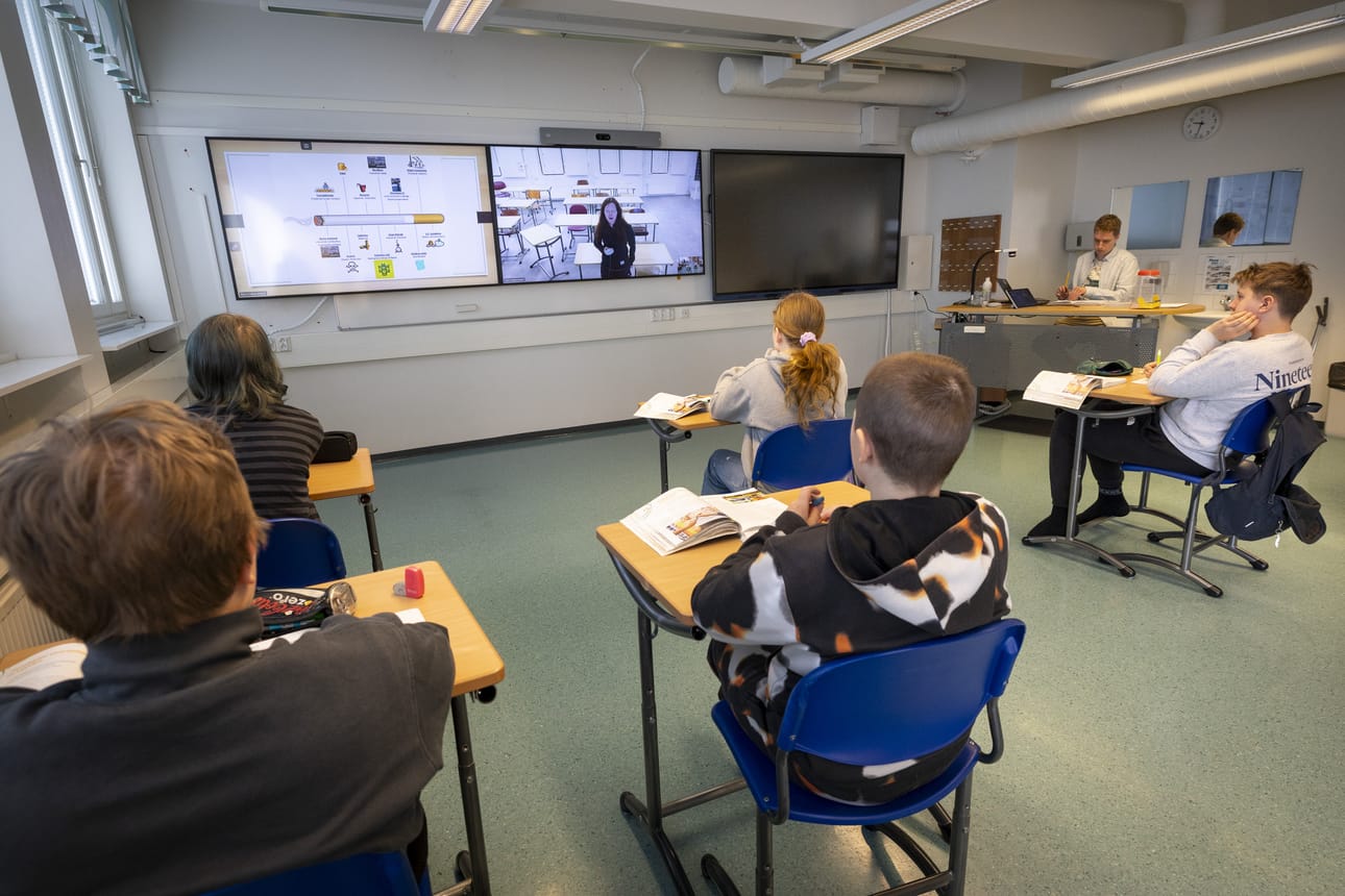 Kuivaniemen koulun seiskaluokkalaiset seuraavat Heini Tammelan opettamaa terveystiedon tuntia etäyhteydellä. Luokassa on mukana aina myös koulunkäynnin ohjaaja, kuvassa taustalla kokeilusta vastaava Lukas Järvenpää.