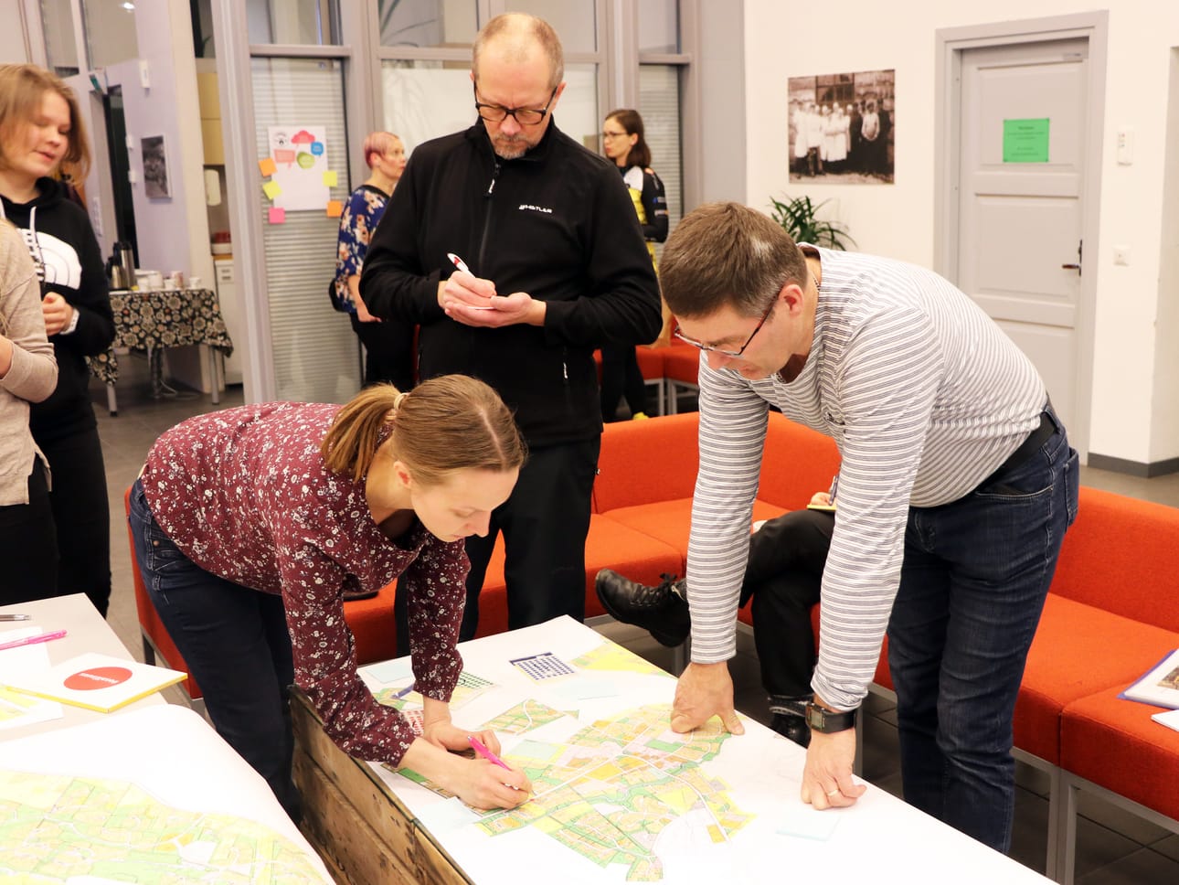 Kari Karppinen kirjoittaa post-it -lappua ja Antti Nevala tutkii yhdessä kehittämispäällikkö Janna Kumpulan kanssa Tyrnävän keskustan karttaa ja sen liikunta-alueita.