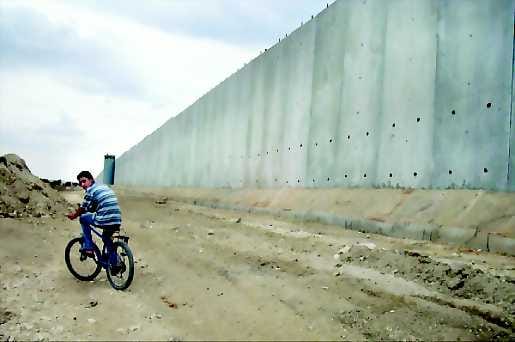Kansat erilleen. Palestiinalainen pyöräili "puolustusmuurin" vierellä Qualqilyan kaupungissa. Israel rakensi muurin vaikeuttaman itsemurhapommittajien pääsyä Länsirannan palestiinalaisalueilta Israeliin.