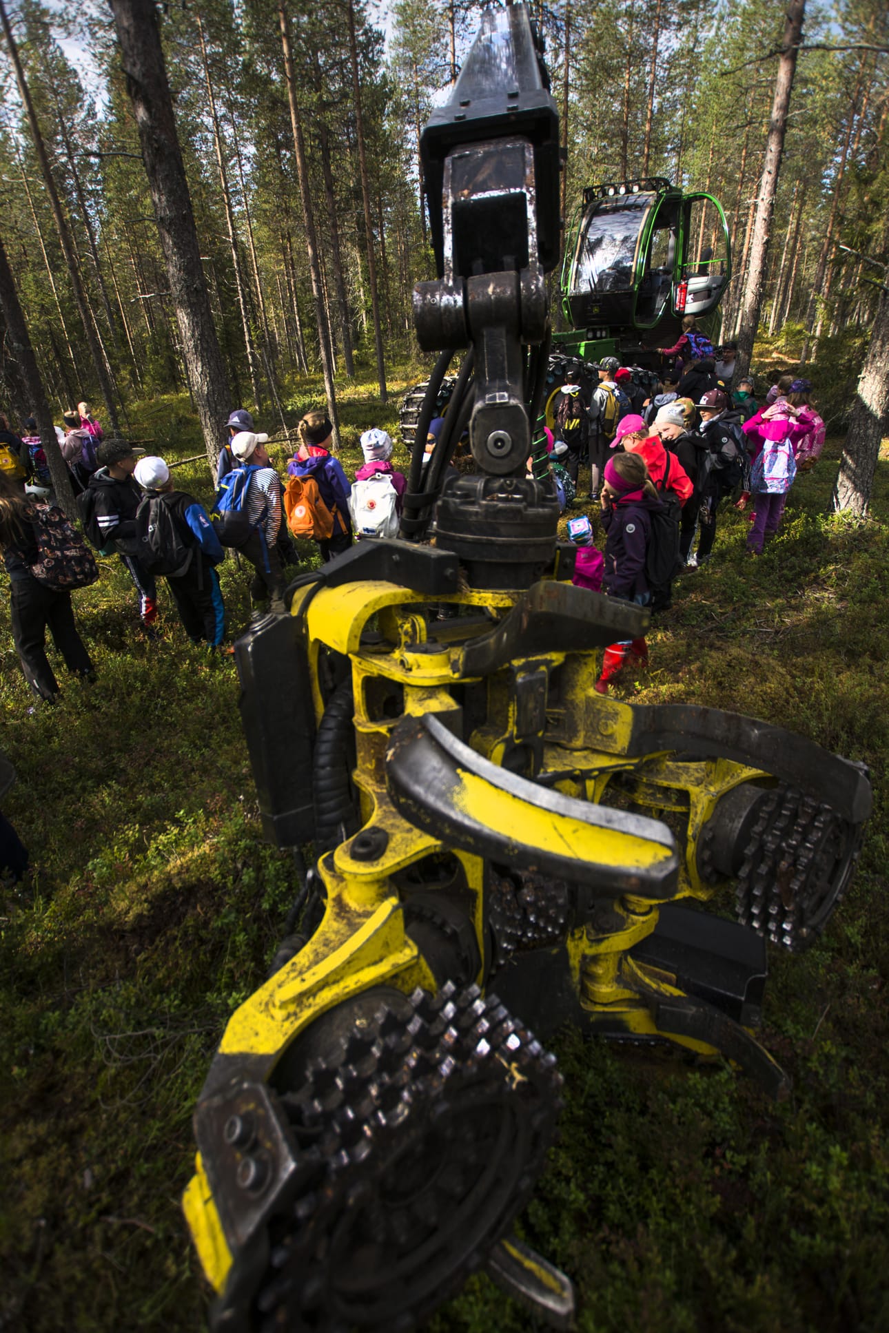 Ismo Nevala nostelee lapsia istumaan metsäkoneen ohjaamoon.