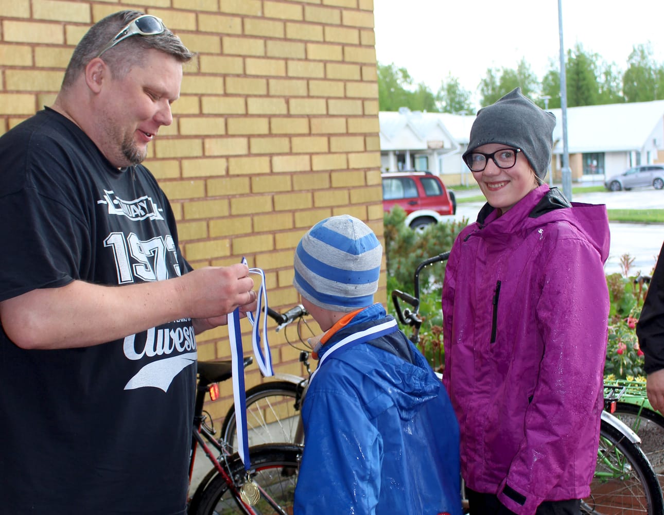 Marko Äijälä pujotti mitalin jokaisen osallistujan kaulaan, vuorossa ruukkilaiset Väinö ja Jenny Ala-aho. Pyöräretkellä oli myös mukana Jaako Ala-aho.