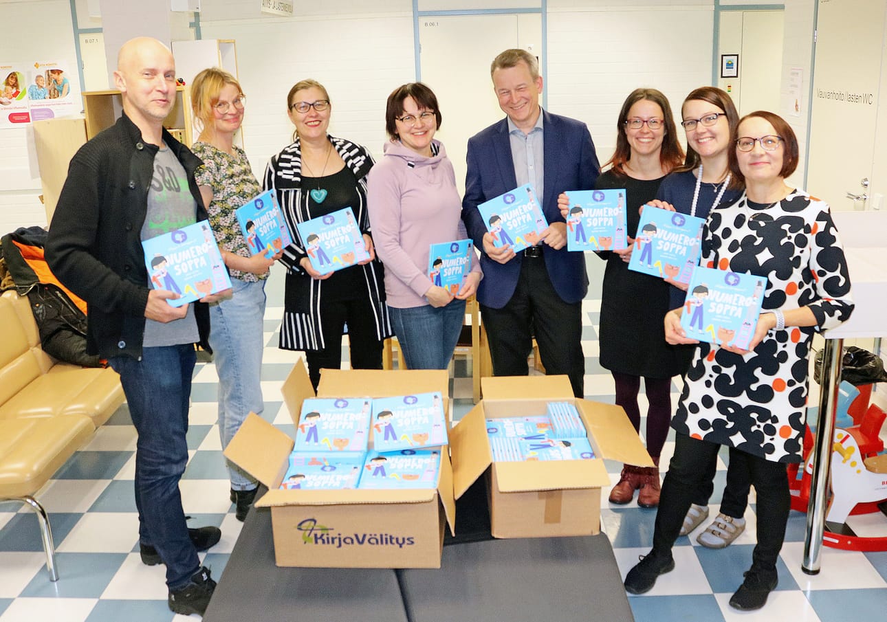 Pudasjärven lastenneuvolaan kokoontui viime viikolla iloinen joukko ihastelemaan värikästä Numerosoppa-lastenkirjaa. Kuvassa kirjailijat Juha Virta ja Marika Maijala, kirjakauppias Tuija Wallgren, kirjalahjoitushankkeen puuha-nainen Tanja Lapinlampi, OP Pudasjärven toimitusjohtaja Pertti Purola, toinen lahjoitushankkeen puuhaaja Outi Nivakoski sekä terveydenhoitajat Maiju Iinatti ja Arja Kaivorinne.
