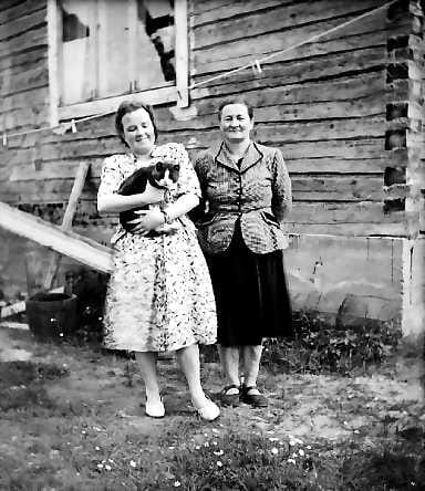 Kaksi naista ja kissa . Matti A. Asikaisen valokuva 1950-luvun alkupuolelta Utajärveltä. Asikaisen valokuvia on esillä Pohjois-Pohjanmaan museossa Oulussa 28.8.-24.10.