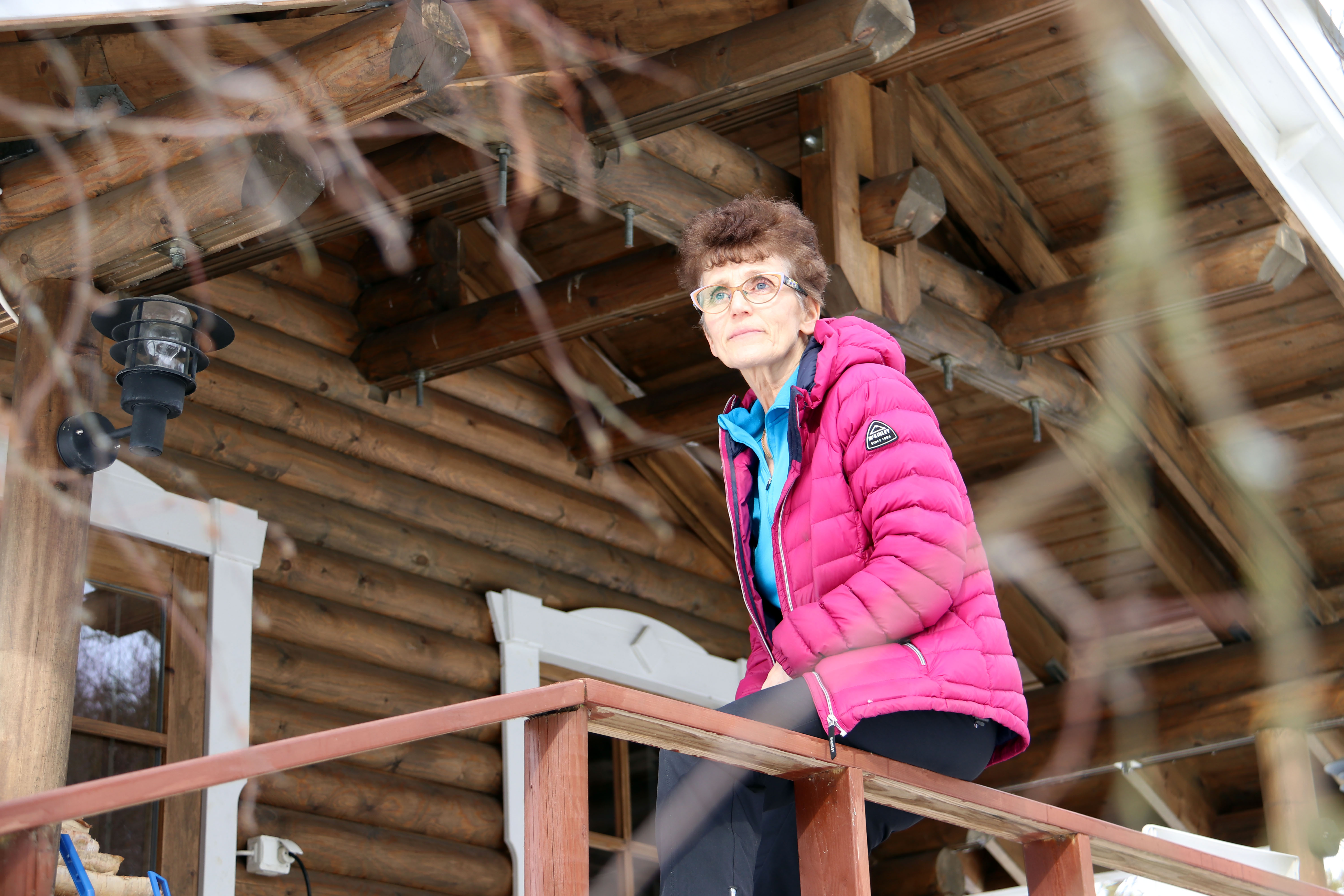 Kaarina Länkinen saunarakennuksen terassilla. Lumijokivarteen rakennettu sauna on majoittujien mieleen.