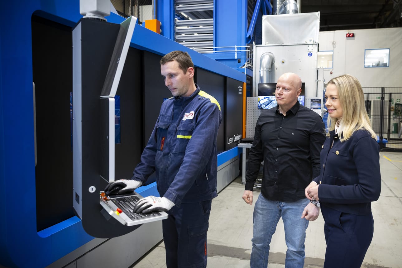 Oleksii Liesov operoi laserleikkuria. Tehtaanjohtaja Petri Koski ja myynti- ja markkinointijohtaja Hanna Pahkala seuraavat.