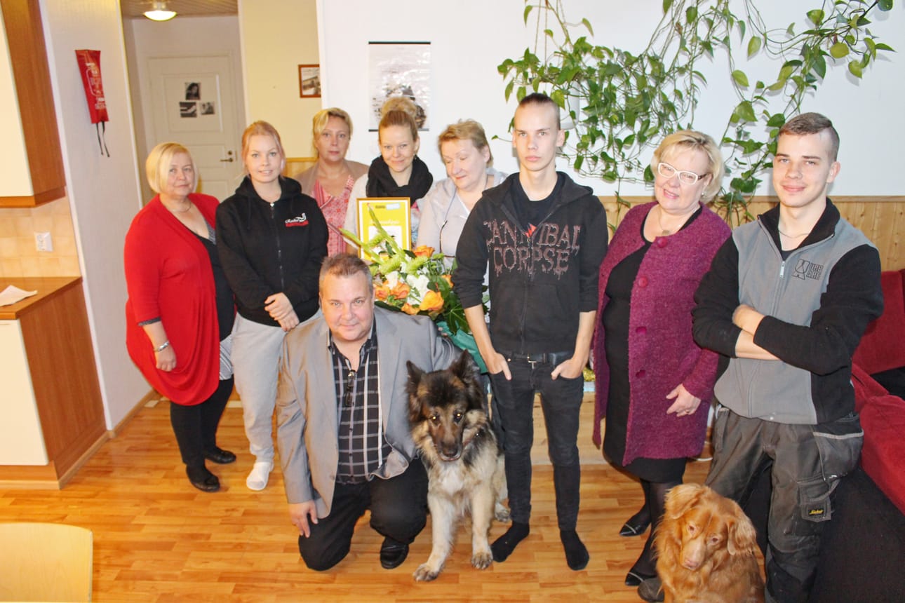 Nuorisokodin henkilökuntaa perhepotretissa. Vasemmalta JHL:n aluetoimitsija Tarja Ollanketo, Suvi-Tuulia Immonen, Tiina Turula, Anu Tolonen, Sirkku Piipari, Saila Pirnes,Tommi Tuhkala ja Jonne Tuhkala. Edessä Kari-Pekka Tuhkala sekä nelijalkaiset työntekijät, saksanpaimenkoira Jeri ja novascotiannoutaja Eetu. Kuva: Kirsi Junttila