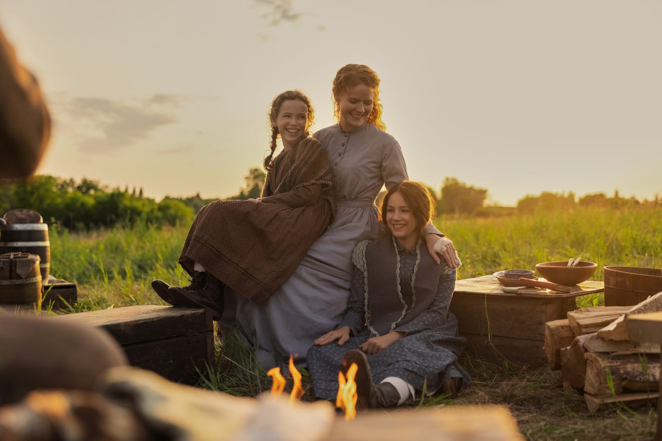 Ingallsin perheen naiset Laura (Alice Halsey), Caroline (Crosby Fitzgerald) ja Mary (Skywalker Hughes) nuotion äärellä Pieni talo preerialla -sarjan ensimmäisessä jaksossa.