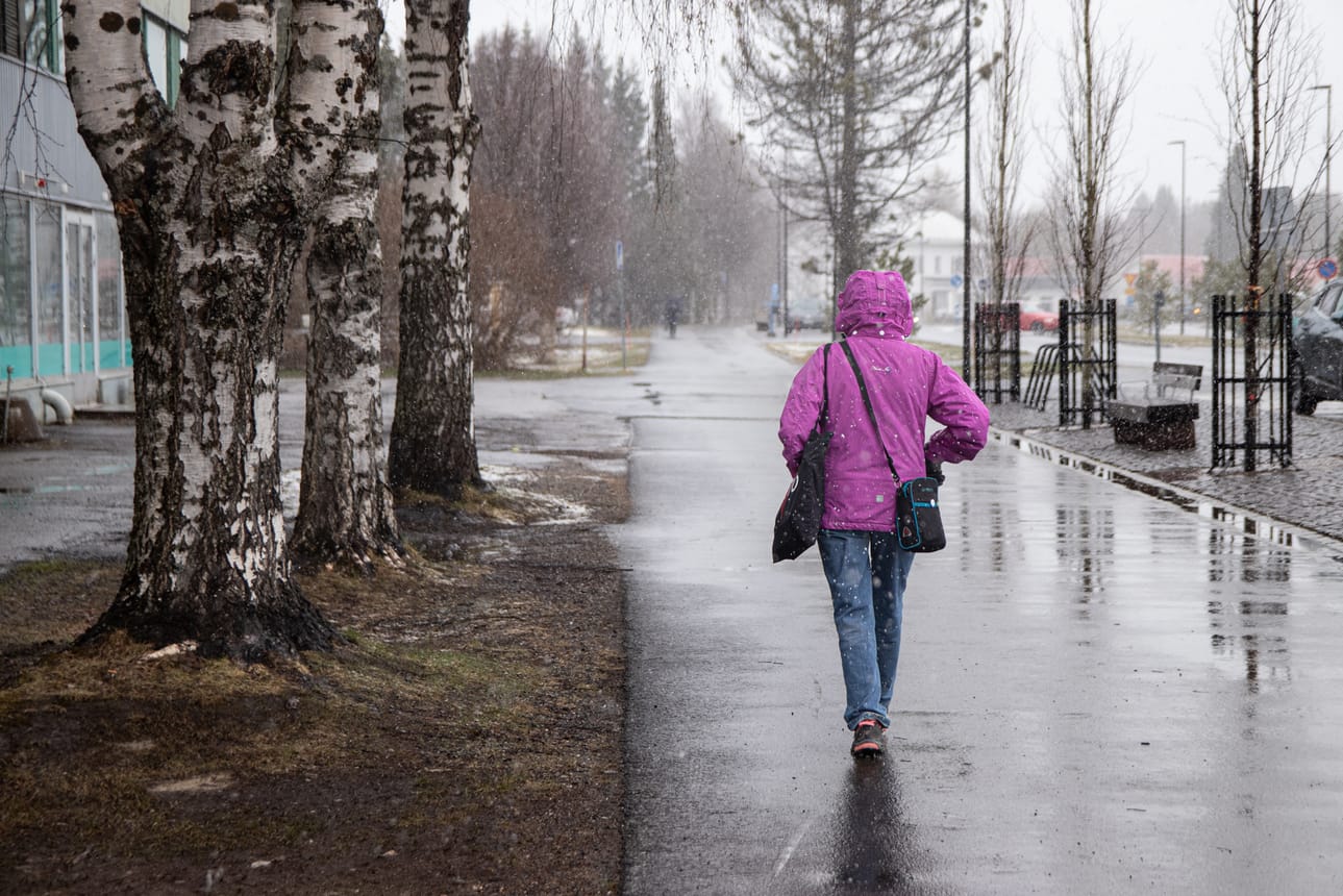 Kuusamossa tuli keskiviikkona lunta ja räntää. Takin huppu oli vedettävä suojaksi.