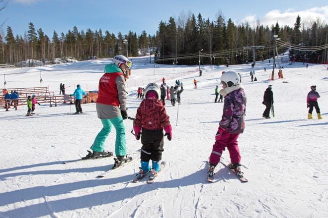 Hiihdonohjaaja Heidi Rantala opastaa Emilia ja Ella Kangasmäkeä laskettelun alkuun. Viisi- ja seitsenvuotiaat vaasalaissiskokset olivat ensimmäistä kertaa Parrassa ja laskettelusuksien päällä. KUVAT: AUNE WARONEN