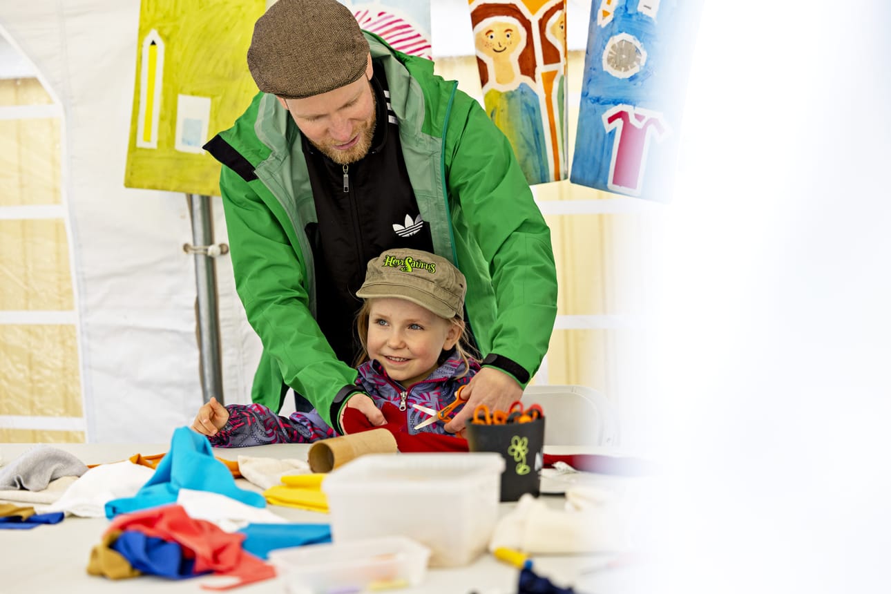 Niilo Rinta-Harri auttoi 4-vuotiasta Auni Rinta-Harria askartelemaan kuplamadon punaisesta kankaasta Mukula-tapahtumassa.