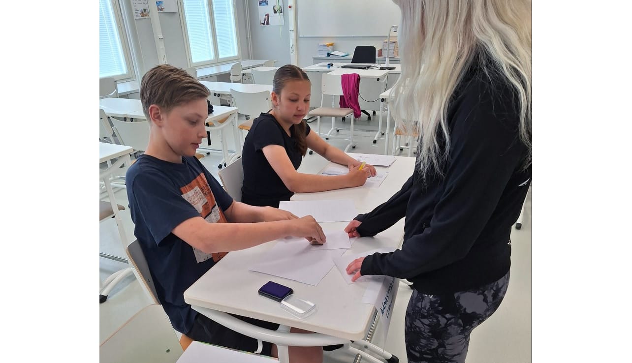 Miro Mäenpää leimasi Kortesjärven yhtenäiskoululla muun muassa Venla Suomelan äänestyslipun. Eveliina Hölsömäki seurasi toimitusta toisena vaalivirkailijana.