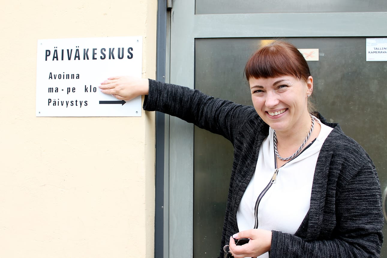 Palveluesimies Katja Karppinen esittelee kylttiä, joka on ollut ruuvattuna Kenttätien palvelukeskuksen ulkoseinään vuodesta 1997 lähtien. Varsinaista päivätoimintaa keskuksessa ei ole kuitenkaan ollut tarjolla ennen kuin nyt parin viikon kuluttua. Seinässä olevat kellonajatkin ovat pielessä. Tuleva toiminta sijoittunee kello 8–15 välille.