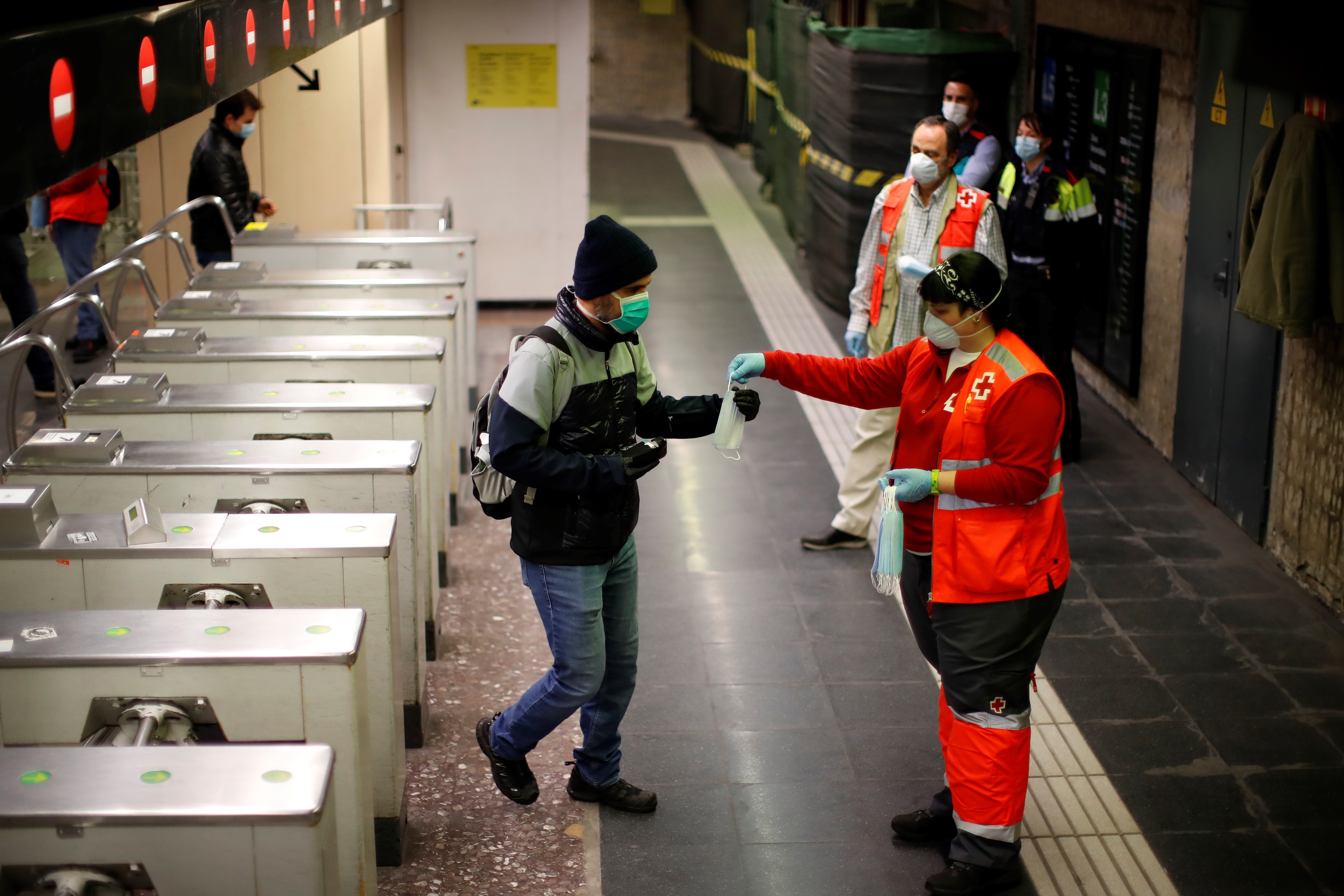 Punaisen Ristin työntekijät jakoivat hengityssuojaimia Espanjassa Barcelonan metroasemilla tiistaina.