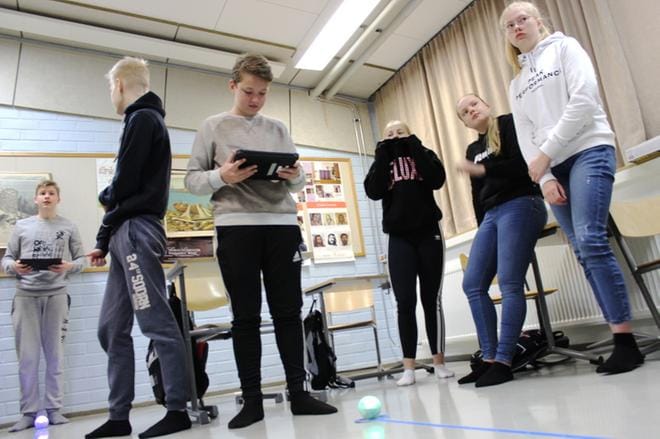Toni Pitkäranta, Rasmus Parvilainen, Urho Leppisaari, Iina Niemelä, Olivia Kytömäki ja Oona Ketola miettimässä, miten pallo ohjelmoidaan kulkemaan lattiaan liimattua nauhaa pitkin. KUVA: LOTTA KALLIO