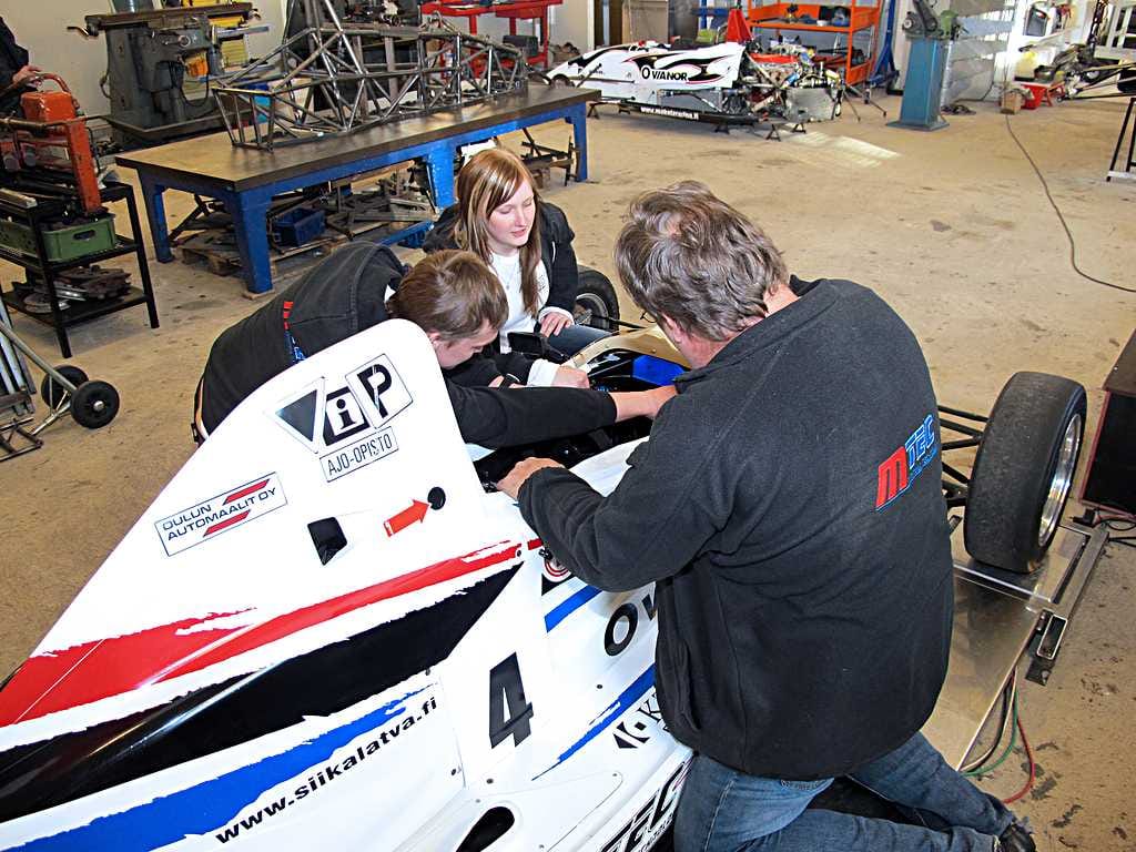 Mtecin vetäjä Markku Mäkelä ja Mäkelä Racing Teamin ajajat Miikka ja Milla Mäkelä sekä Miikan ensi kesän kilpa-auto. Takana pöydällä näkyy seuraavana valmistuvan auton runko ja taustalla on myös yksi huoltoon tullut vanhempi Formula Ford.