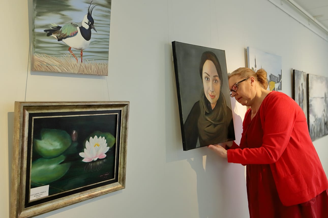 Anu Laulumaa-Julin asettelee maalauksia paikoilleen. Kehitystä tapahtuu, opettaja iloitsee.
