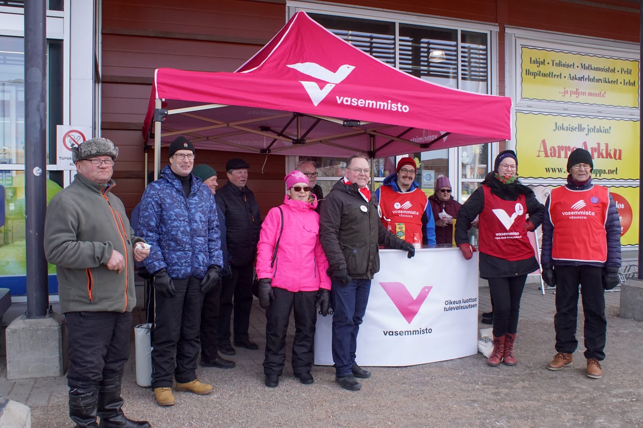 Vasemmiston vaalikojulla ehdokkaat ja äänestäjiä yhteiskuvassa.