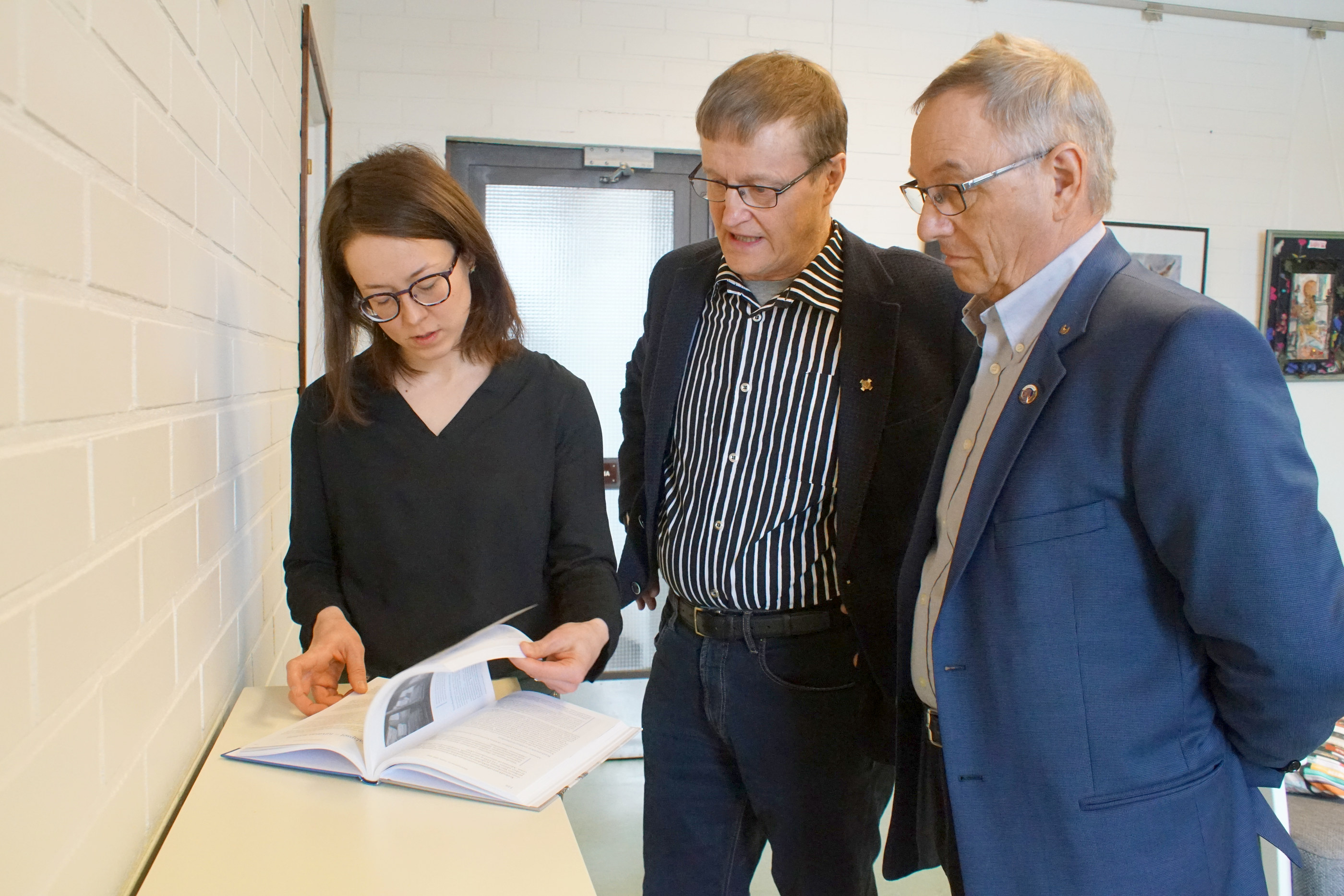 Paavo Ervasti ja Vesa Holmström luovuttivat kirjan kirjastonjohtaja Outi Nivakoskelle ja lainaajien käyttöön.