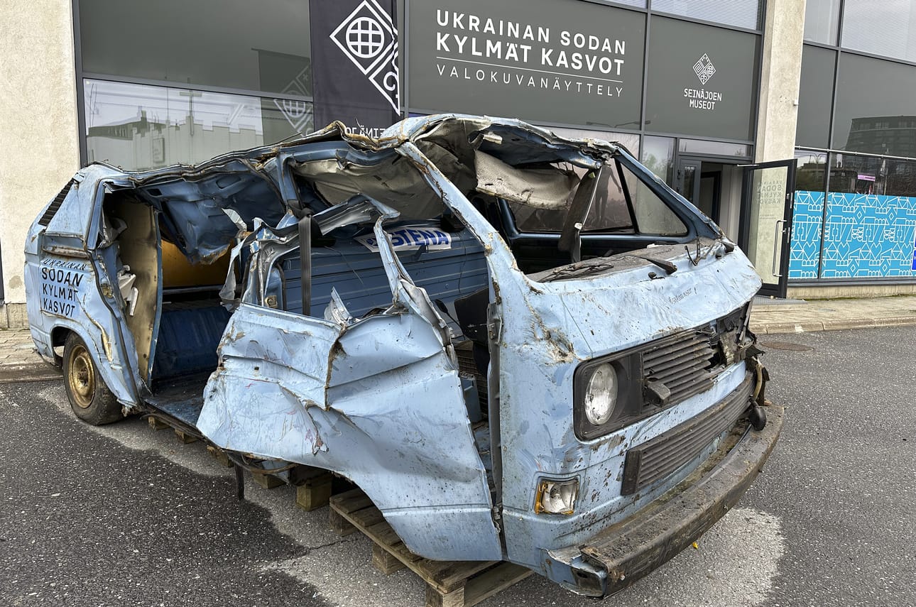 Murskaantunut pakettiauto ohjaa yleisöä kohti näyttelyn sisäänkäyntiä. Auto on toimitettu seinäjokelaiselta romuttamolta.