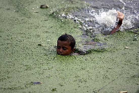 Poika uimassa saasteiden likaamassa joessa Bangladeshissa.