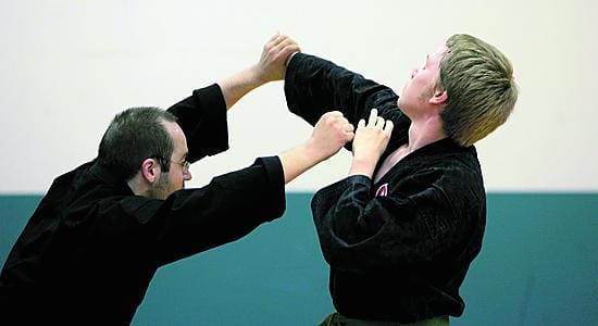 Ismo Saanio näyttää maassa makaavalle Jussi Niittyviidalle miten bo-keppiä käytetään.