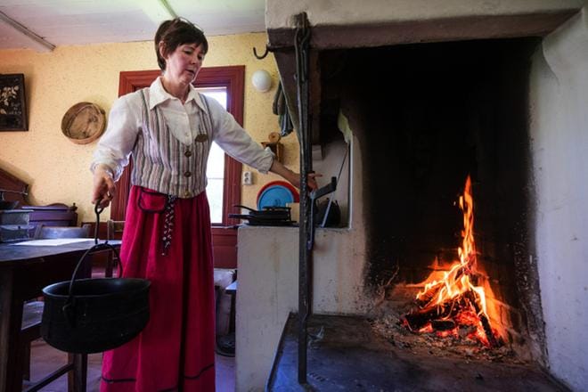 Tutkija Susanne Lagus kantaa 1700-luvulta peräisin olevaa pataa. – Työ oli raskasta, tämä painaa varmasti kymmenen kiloa. Kun sen täyttää, se painaa vielä enemmän, hän kertoo. KUVAT: JARNO PELLINEN