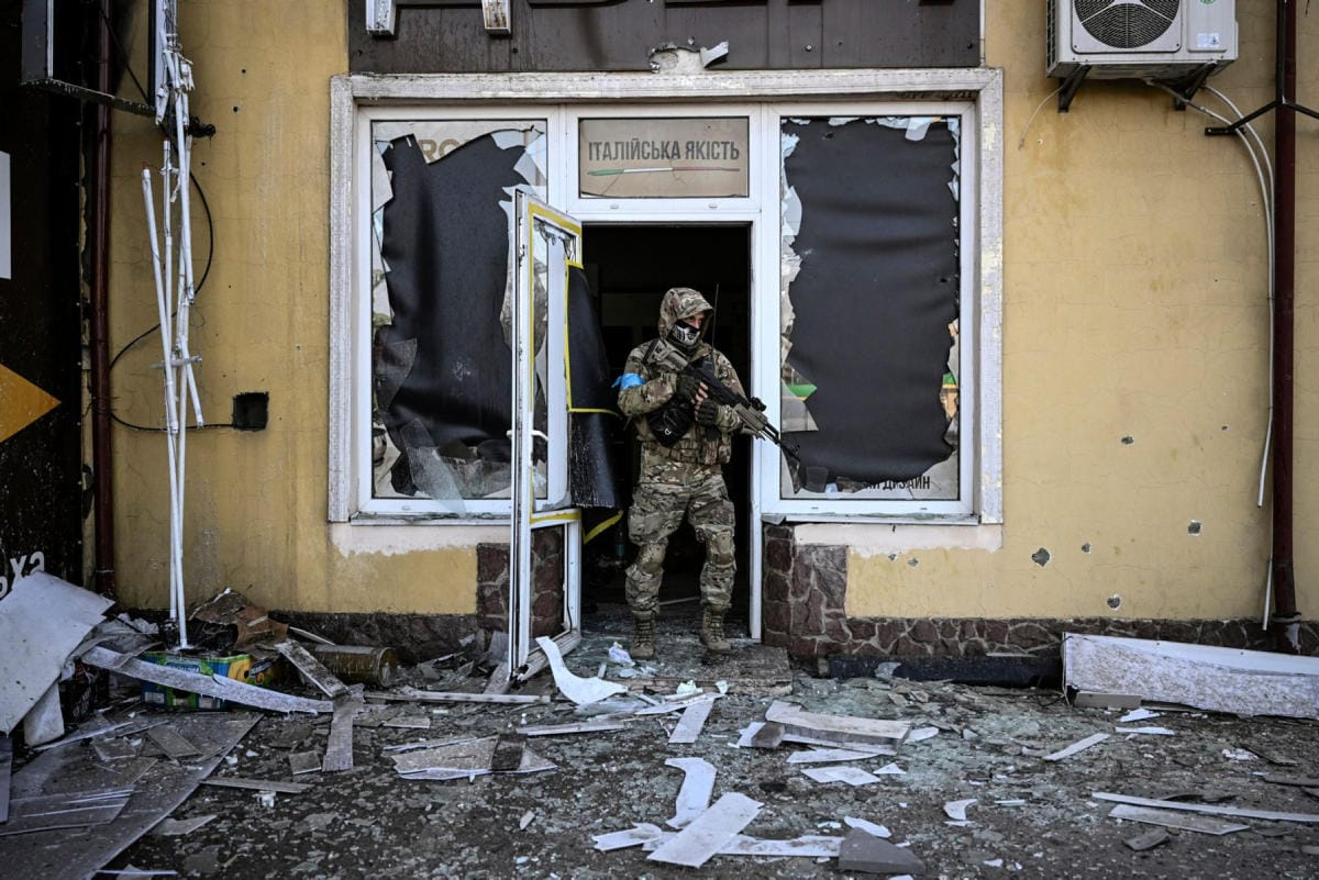 Ukrainalaissotilas poistumassa vaurioituneesta talosta Kiovassa 11. maaliskuuta. LEHTIKUVA / AFP