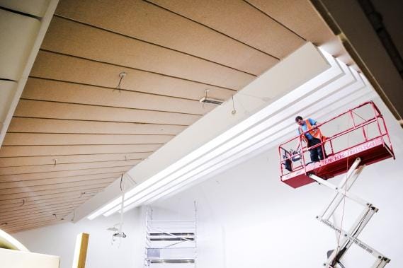 Projektipäällikkö Jyrki Karikangas asentaa Seinäjoen kaupungintalon valtuustosalin kattoikkunoiden palkkeihin ledvalonauhaa. – Valolähde on huomaamaton, mutta lopputuloksena on hienoa epäsuoraa valoa, kaupunginarkkitehti Jussi Aittoniemi kuvailee. KUVAT: KRISTA LUOMA