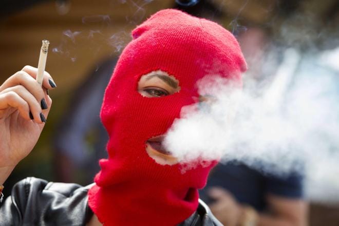 Pussy Riotin jäsen tupakoi Hollannissa järjestetyillä festivaaleilla. Värikkäät kommandopipot ovat ryhmän tavaramerkki. KUVA: VINCENT JANNINK/EPA