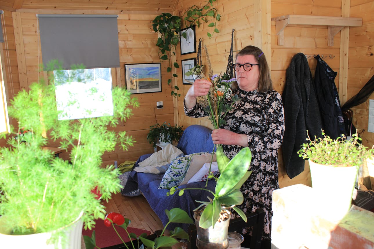 Raisa Nurminen teki kukkakimppua mökissä, joka rakennettiin hänelle työtilaksi perheen kotitilan Kaisaniemen pihaan Lapväärttiin. ‑ Mökki on valoisa ja täällä viherkasvit ja kukat viihtyvät.