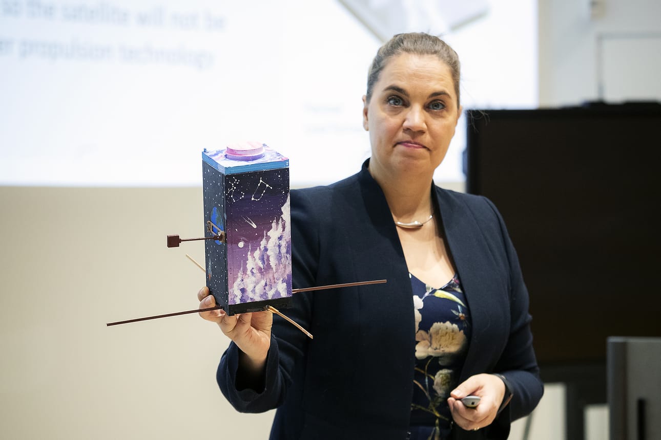 Professori Heidi Kuusniemi esittelee vimpeliläisten koululaisten askartelemaa mallia Merenkurkun satelliitista. Varsinaisen satelliitin matkassa lähtee avaruuteen myös lasten ja nuorten piirustuksia.