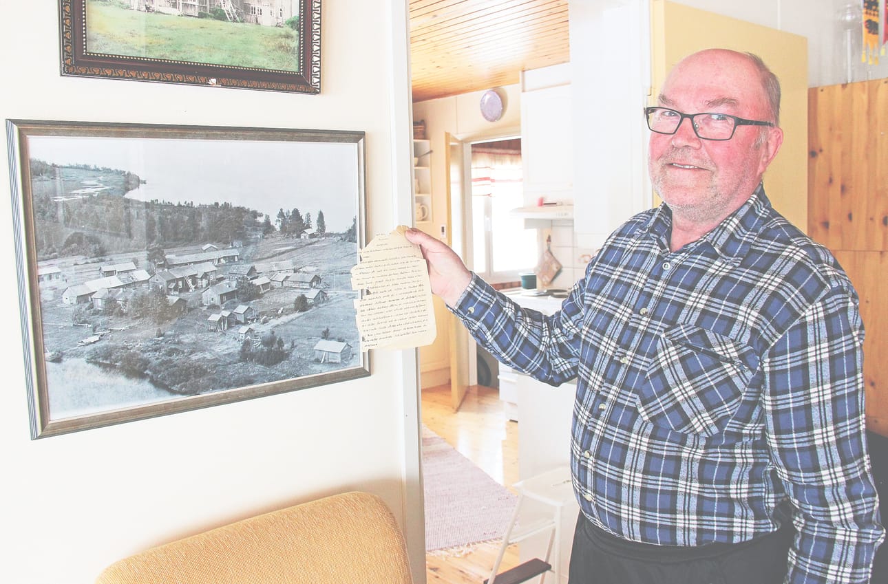 Pekka Jussila näyttää vuosikymmenet tallessa ollutta paperinpalaa. Seinällä on kuva Liikasen kartanosta.