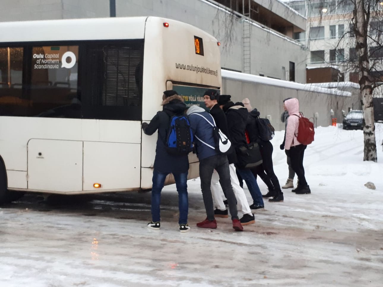 Nuorisoporukka yritti saada bussia liikenteeseen liukkaassa ylämäessä.