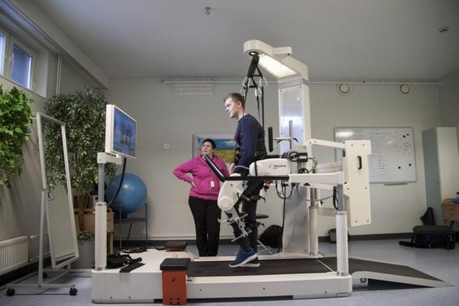Emil Leskinen harjoittelee kävelyä Lokomat-kävelyrobotin kanssa. Takana on jo lähes 2 kilometrin taival. Kuntoutusta seuraa fysioterapeutti Sirpa Karkkonen. KUVA: