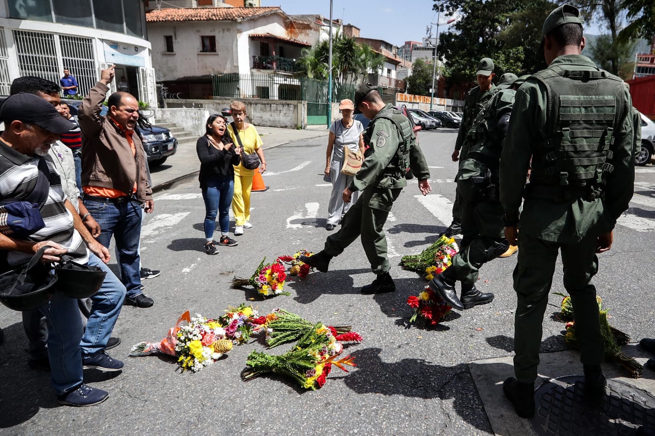 Venezuelan armeijan sotilaat potkivat kumoon kukkia, joita ihmiset olivat tuoneet vankilassa kuolleen merivoimien kommodorin Rafael Acostan muistoksi pääkaupungissa Caracasissa tällä viikolla.