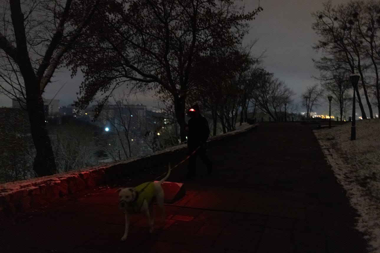 Kiovassa ja Lvivissä ollaan tällä hetkellä ilman sähköjä Venäjän iskujen vuoksi. Kuvassa mies ulkoiluttaa koiraa Kiovassa sähkökatkon aikaan 17. marraskuuta.